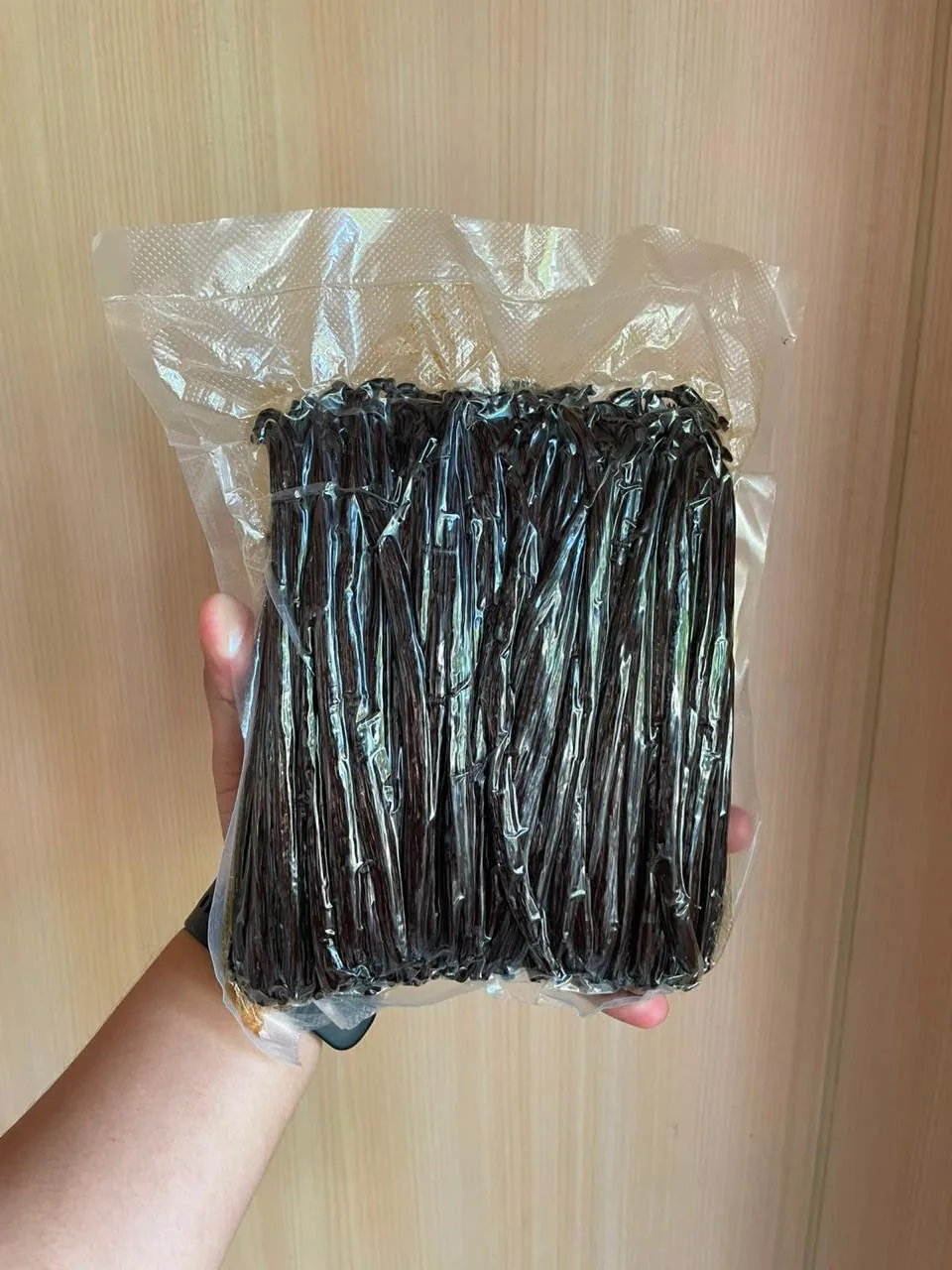Vacuum-sealed bag of vanilla beans held in hand